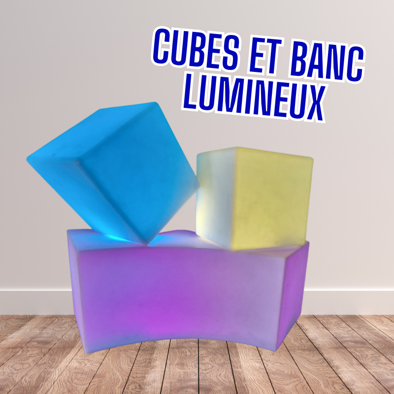 Cubes et banc illuminés par des couleurs bleu, jaune et rose. 2 cubes sont posés sur le banc.
