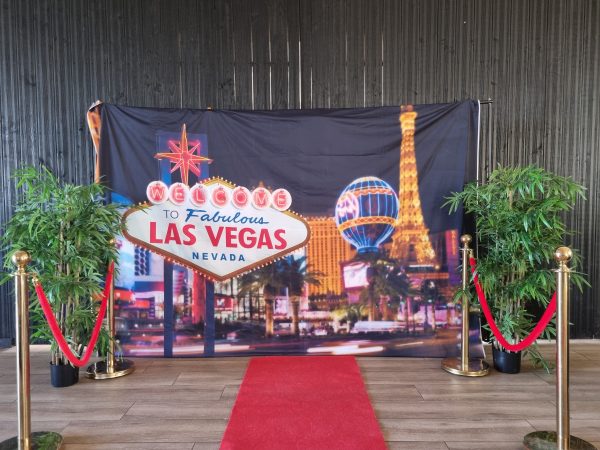 Une bâche "Las Vegas" avec en décoration un tapis rouge, des poteaux dorés et des arbres factices
