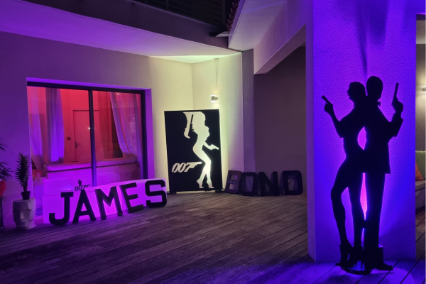 Des silhouettes ainsi que les lettres james bond géantes sont posées contre le mur et éclairées par des spots lumineux
