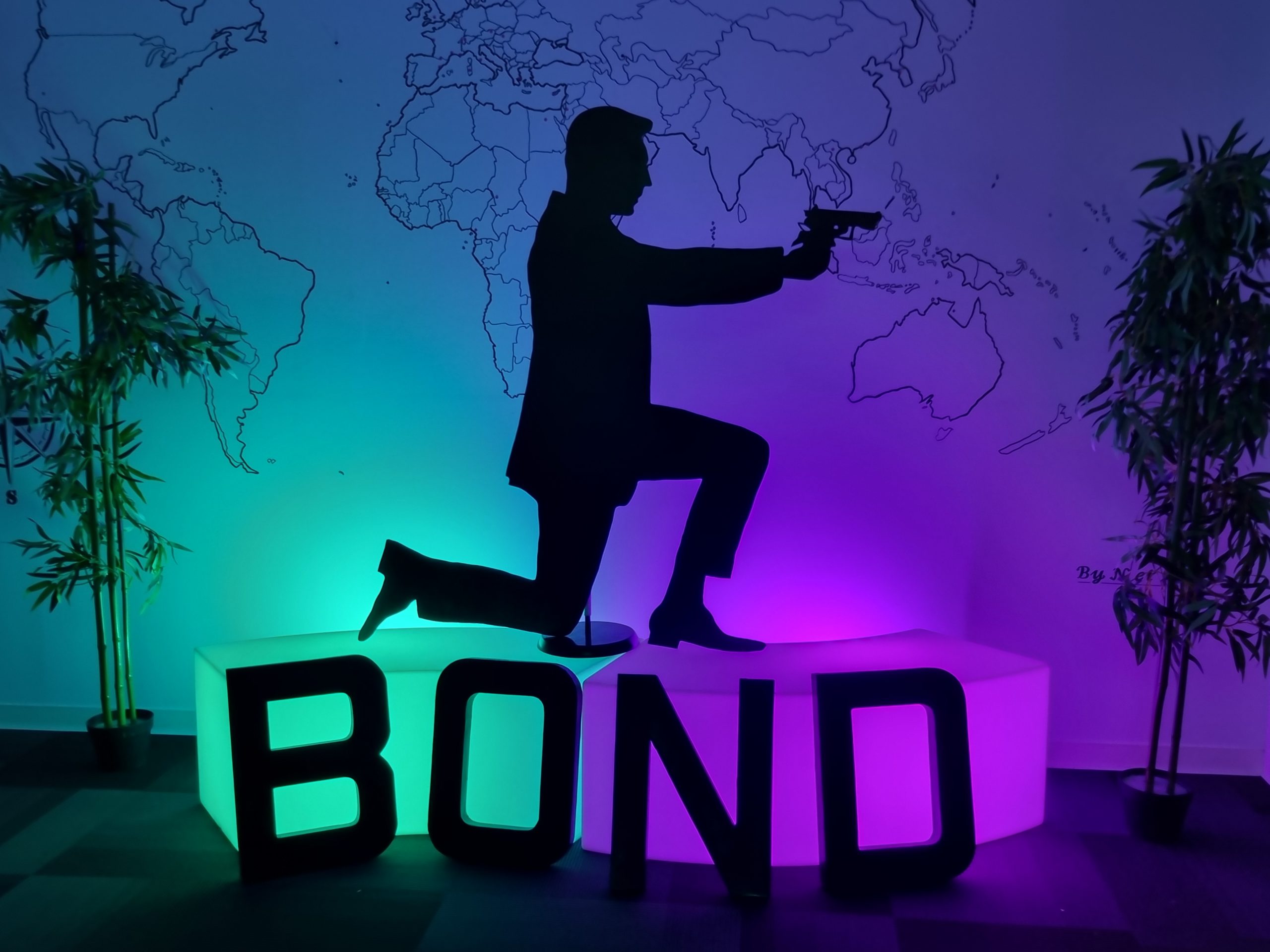 Décoration James Bond avec une silhouette de celui-ci posé sur des bancs lumineux où des lettres géantes avec écrit "Bond" sont posés contre.