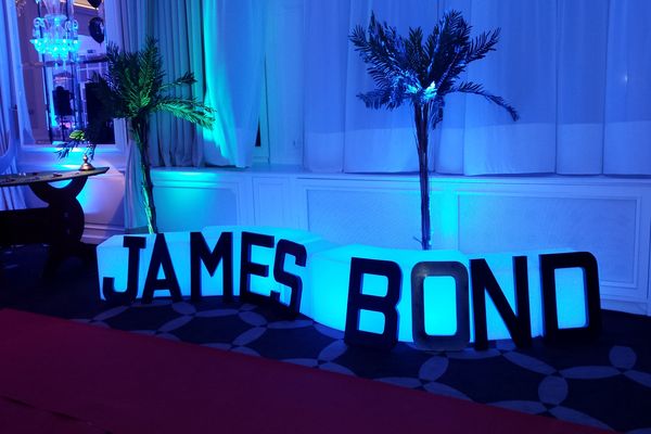 lettre géantes avec écrit "james bond" posées contre des banc lumineux bleus
